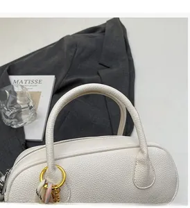 Detail of white lychee leather handbag with sturdy handles and gold ring hardware