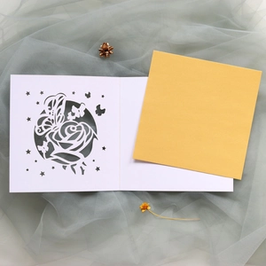 Détail de l'invitation de mariage découpée au laser avec roses, papillons et insert jaune