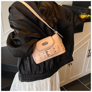 Détail d'un sac seau en cuir abricot avec fermoir rotatif en métal et sangle décorative