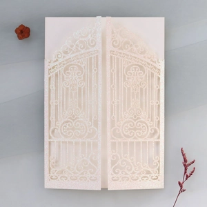 Detail of laser-cut glitter wedding invitation with elegant hollow gate design and inner card