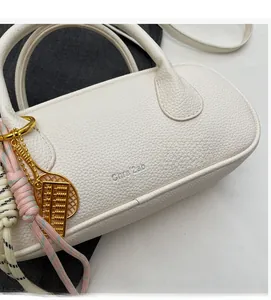 Close-up of white pebble leather barrel bag with silver logo and gold abacus charm detail