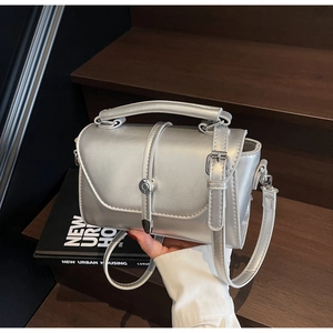 Detail of silver metallic mini crossbody bag with fold-over flap and metal buckle
