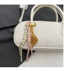 Close-up of golden abacus bag charm with woven cords on white lychee pattern handbag