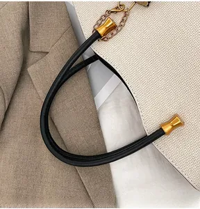 Detail of the cream textured tote bag with black leather handle and gold hardware