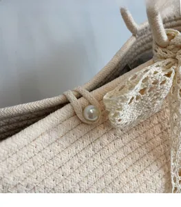 Close-up of woven straw tote bag with pearl clasp and delicate lace bow decoration