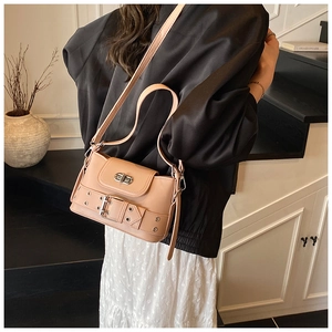 Détail du sac bandoulière en cuir beige avec œillets métalliques et bandoulière réglable