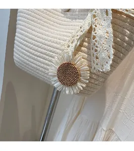 Detail of woven straw tote bag featuring a sunflower pendant and white lace ribbon