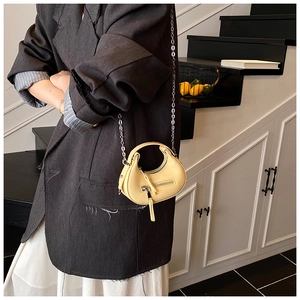 Detail of pale yellow crescent bag with textured leather and silver chain strap