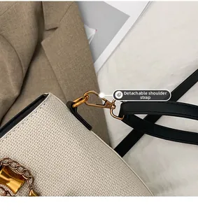 Detail of the golden metal hook and detachable strap on the woven shoulder bag