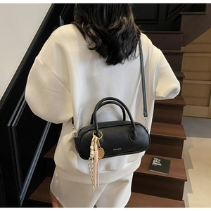 Detail of black lychee grain leather handbag with silk scarf and tennis racket charm