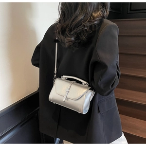Silver metallic crossbody mini bag with handle shown on shoulder in modern setting