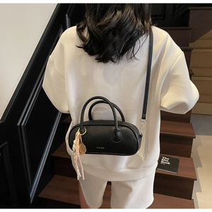 Close-up of black lychee grain leather pillow bag with stylish tennis racket charm detail