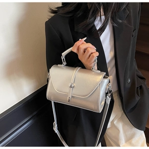 Close-up of shiny silver rectangular handbag featuring metallic lock and adjustable strap