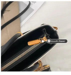 Detail view of smooth golden zipper and high-quality hardware on black leather tote bag