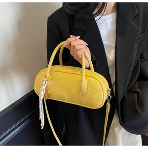 Close-up of bright yellow lychee texture boston bag with elegant silk scarf accessory