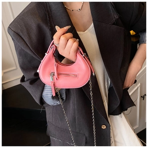 Detail of pink pebbled leather crescent bag with decorative zipper and silver chain strap