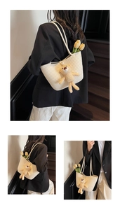 Detail of woven straw tote bag featuring a cute plush bear charm and cotton rope texture