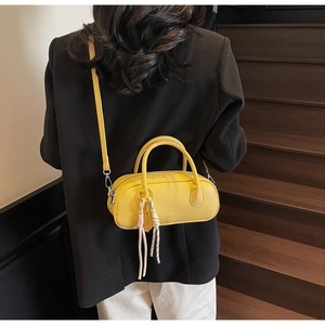 Detail of yellow lychee texture bag with tennis racket charm and tassel on model