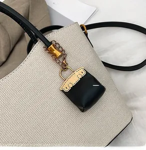 Detail of white lychee pattern tote with black mini bag charm and gold chain links
