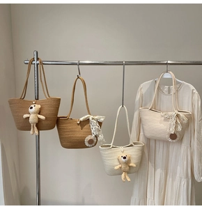 Detail of hand-woven straw tote bags with plush bear, lace bow and daisy charms