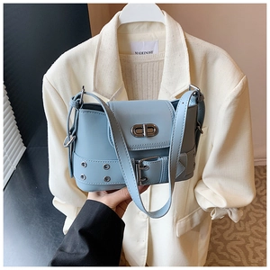 Détail d'un sac seau en cuir bleu clair avec fermoir rotatif argenté et œillets en métal