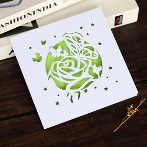 Détail d'une carte découpée au laser avec rose et papillon sur fond de bois