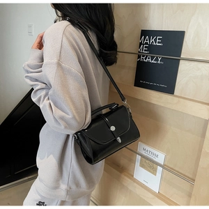 Model showing a black crossbody bag with silver buckle and smooth leather texture