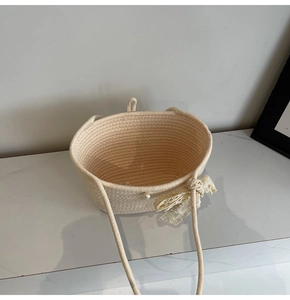 Detailed texture of hand-woven straw tote with elegant lace bow and pearl accent
