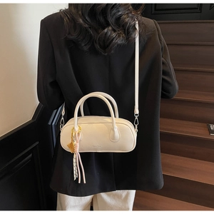 Detailed close-up of a creamy white litchi pattern bowling bag with a silk tassel charm