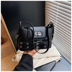 Détail du sac seau en cuir noir avec ceintures à œillets argentés et fermoir rotatif