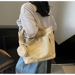 Détail d'un sac cabas en toile beige avec poches latérales et petit porte-monnaie rond
