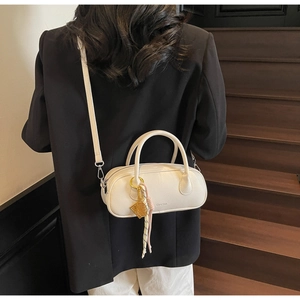 Close-up of white lychee pattern pillow bag with tennis racket charm on wooden stairs