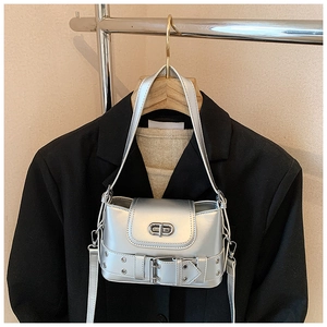 Détail du sac argenté métallisé avec fermoir ovale et ceinture décorative à œillets