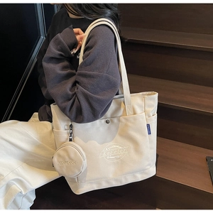 Sac fourre-tout en toile crème avec mini pochette amovible sur un escalier en bois