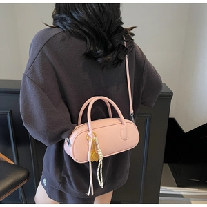Detailed back view of pink lychee textured boston bag worn as a crossbody with charm