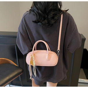 Detailed view of pink lychee texture leather barrel bag with decorative woven charms