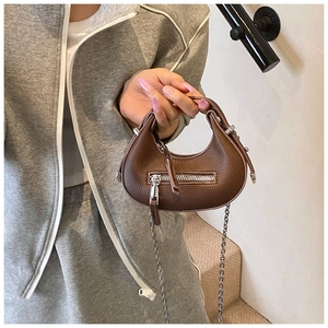 Detail of dark brown pebble leather mini crescent bag with silver zippers and chain strap