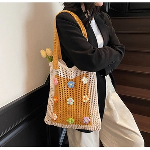 Détail d'un sac cabas en crochet fait main avec des fleurs 3D colorées sous une lumière douce