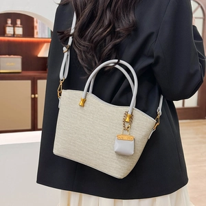 Detail of woven tote bag with gray leather handles and elegant gold hardware accents