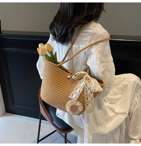 Detail of woven straw tote bag featuring white lace bow, sunflower patch, and pearl button