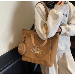 Gros plan d'un sac cabas en toile marron avec broderie blanche et pochette ronde amovible