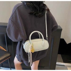 Detail of light grey lychee texture pillow bag with braided knot and gold metal accents