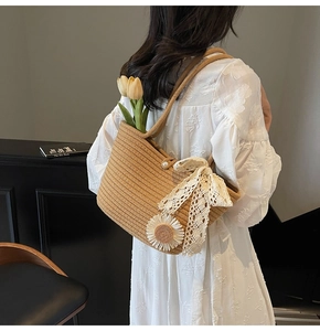 Detail of straw tote bag featuring white daisy appliques and a delicate lace bow