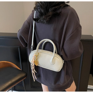 Detail of light gray lychee grain leather crossbody bag with tennis racket charm