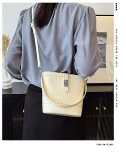 Close-up of off-white crocodile embossed bucket bag with silver metal lock detail