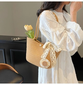 Detail view of woven straw tote bag featuring a lace bow, sunflower decor, and pearl clasp