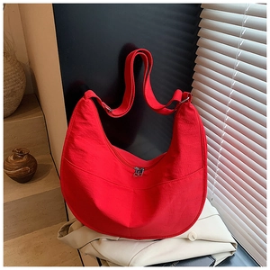 Detail of red crescent shoulder bag featuring silver zipper and textured nylon fabric