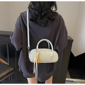Rear view of a model wearing a beige lychee texture boston bag with tennis racket charm