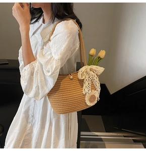 Detailed close-up of woven tote bag with lace bow and sunflower on white dress