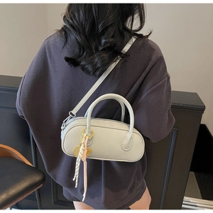 Detailed back view of a light gray lychee leather Boston bag worn by a female model